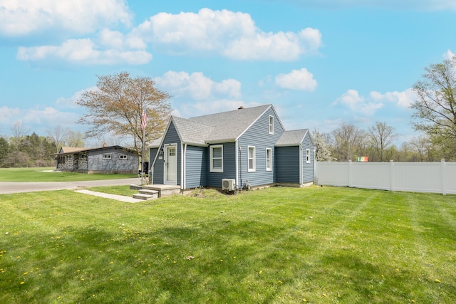 exterior space featuring a shingled roof, fence, and a front yard