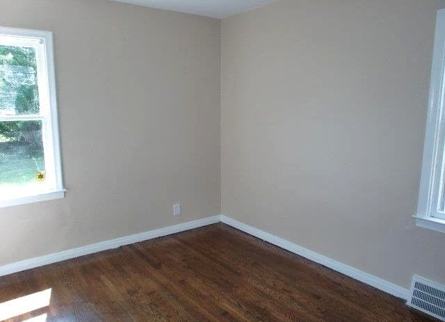 19724 Elkhart St, Harper Woods, MI 48225 - empty room featuring baseboards, visible vents, a wealth of natural light, and dark wood-type flooring