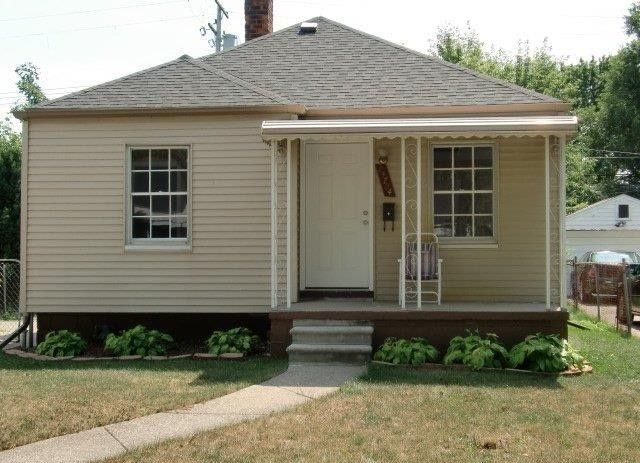 19724 Elkhart St, Harper Woods, MI 48225 - bungalow-style home with a porch, a shingled roof, a front yard, and a chimney
