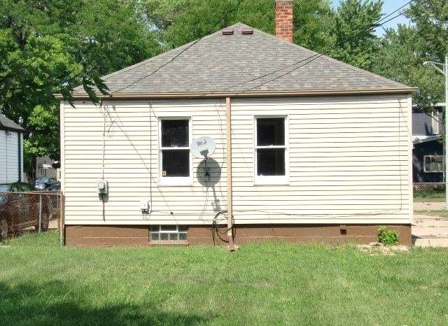 19724 Elkhart St, Harper Woods, MI 48225 - rear view of property featuring a yard, fence, a chimney, and roof with shingles