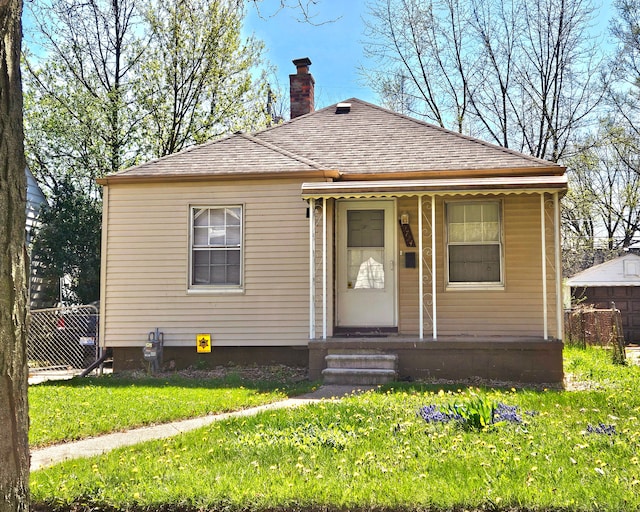 19724 Elkhart St, Harper Woods, MI 48225 - view of front of home featuring fence, a chimney, a shingled roof, and a front lawn