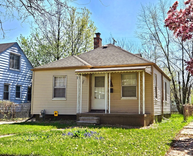19724 Elkhart St, Harper Woods, MI 48225 - view of front of house with roof with shingles, fence, a chimney, and a front yard