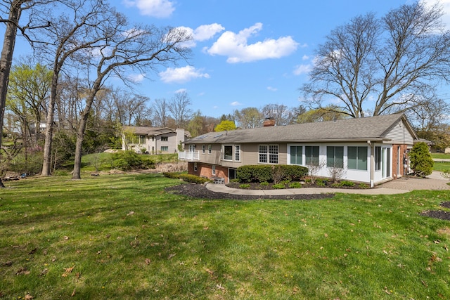 back of property with a chimney, brick siding, and a lawn