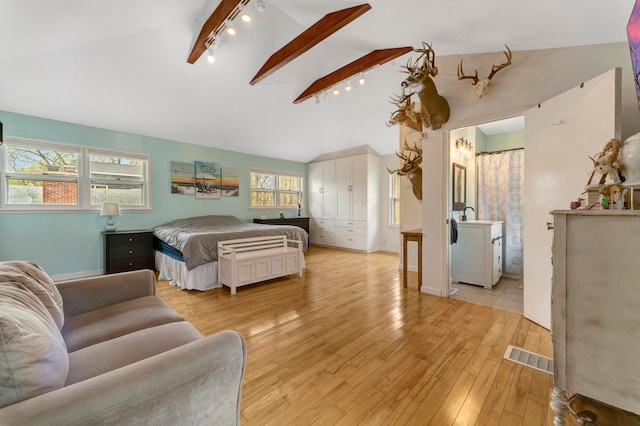 bedroom with rail lighting, lofted ceiling with beams, visible vents, and light wood-type flooring