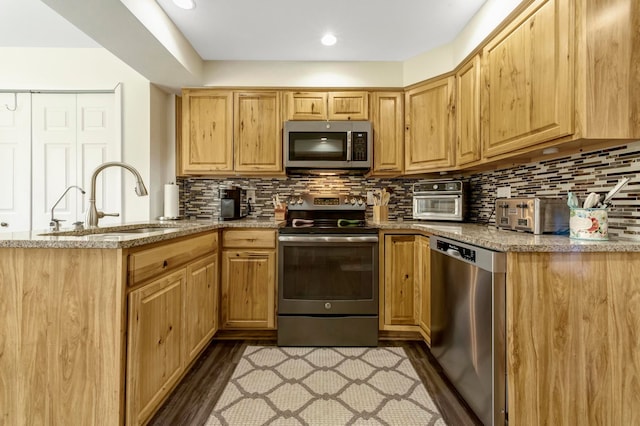 kitchen with dark wood-style flooring, light stone counters, a sink, stainless steel appliances, and tasteful backsplash