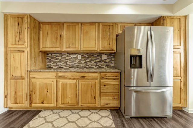 kitchen with light brown cabinetry, light stone counters, stainless steel fridge, tasteful backsplash, and dark wood-type flooring