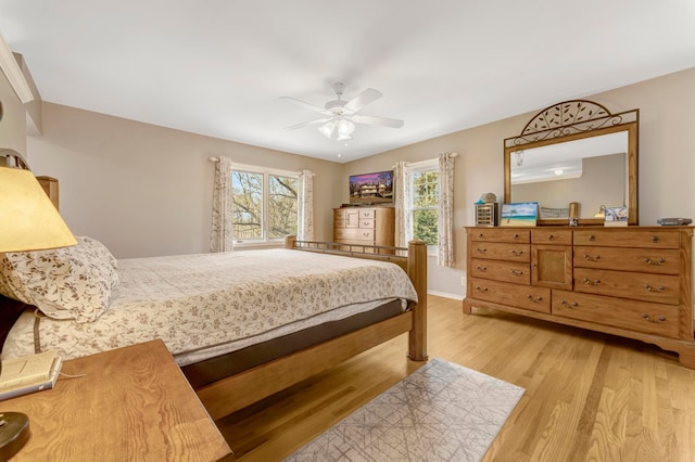 bedroom with ceiling fan, multiple windows, and light wood-style flooring