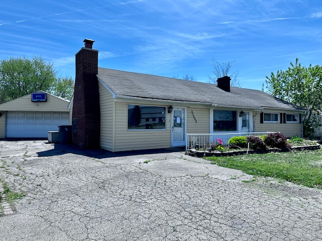 view of front of home featuring an outdoor structure, covered porch, a chimney, and a detached garage