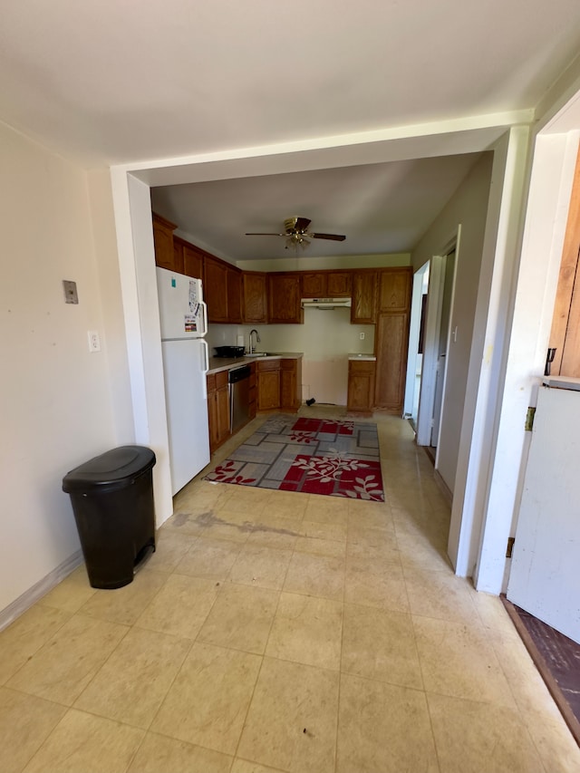kitchen with ceiling fan, stainless steel dishwasher, brown cabinets, a sink, and freestanding refrigerator