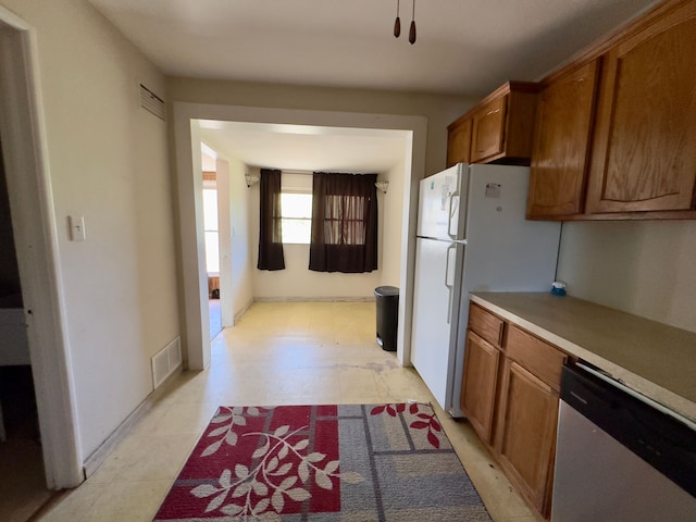 kitchen featuring stainless steel dishwasher, visible vents, brown cabinetry, and light countertops