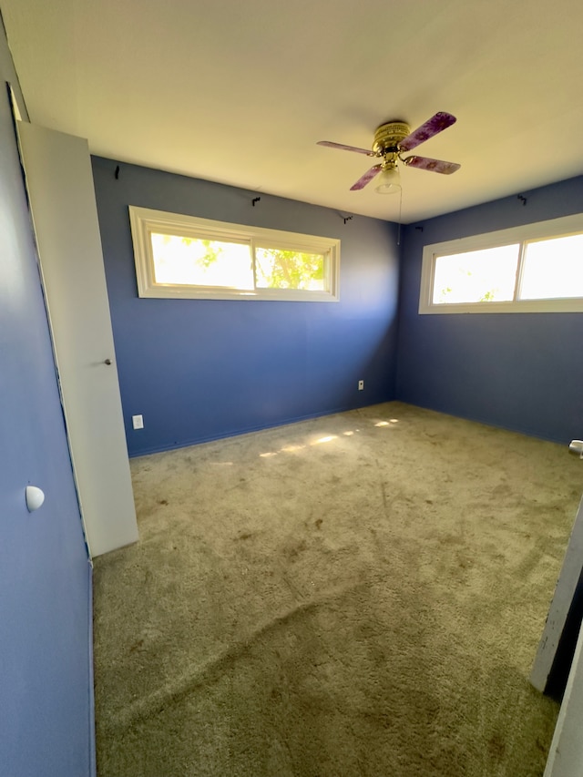carpeted spare room featuring ceiling fan and a wealth of natural light