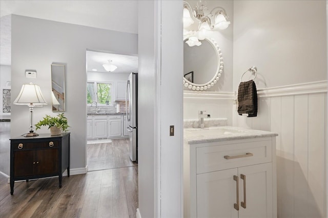 bathroom with an inviting chandelier, wood finished floors, two vanities, and a sink