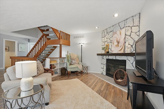 living area with wood finished floors, a fireplace, visible vents, baseboards, and stairway