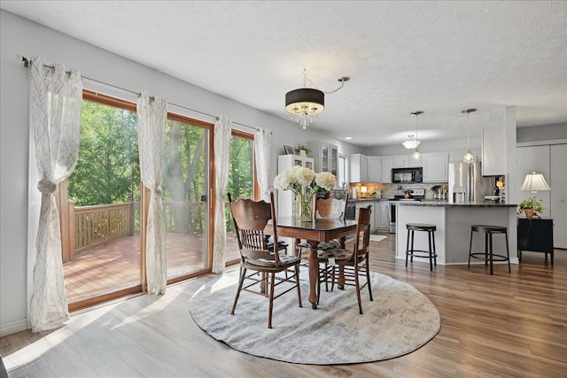 dining space with a textured ceiling, wood finished floors, and baseboards