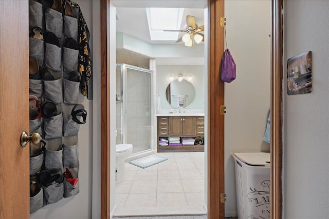 bathroom with a stall shower, a ceiling fan, tile patterned floors, vanity, and a skylight