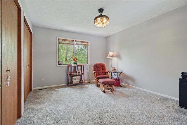 living area with baseboards, carpet flooring, visible vents, and a textured ceiling