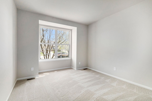 spare room featuring baseboards, visible vents, and light carpet