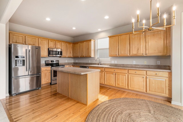 kitchen with a center island, a sink, an inviting chandelier, stainless steel appliances, and light wood-style flooring