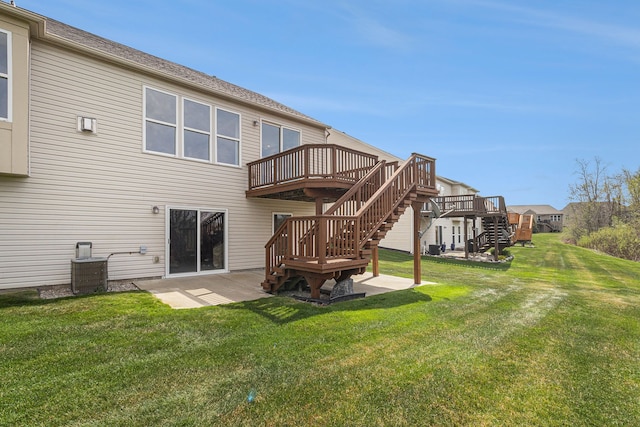 rear view of property with a lawn, a wooden deck, stairway, and a patio