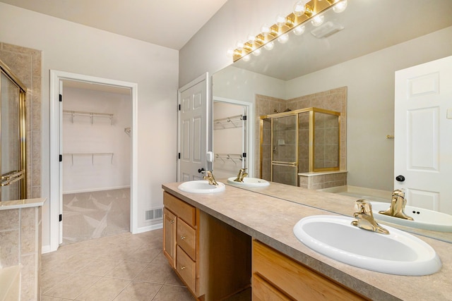 bathroom with double vanity, a shower stall, a sink, and tile patterned flooring