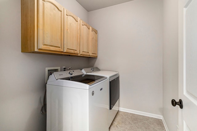 washroom featuring washer and dryer, light tile patterned flooring, baseboards, and cabinet space