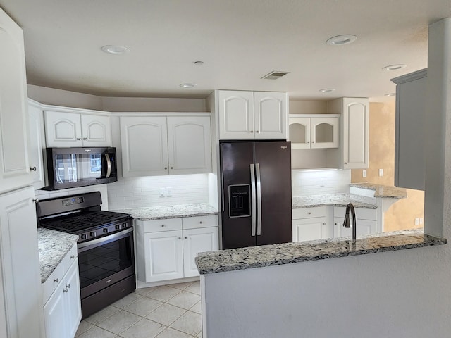 kitchen with a peninsula, stainless steel gas range, fridge with ice dispenser, tasteful backsplash, and light stone counters