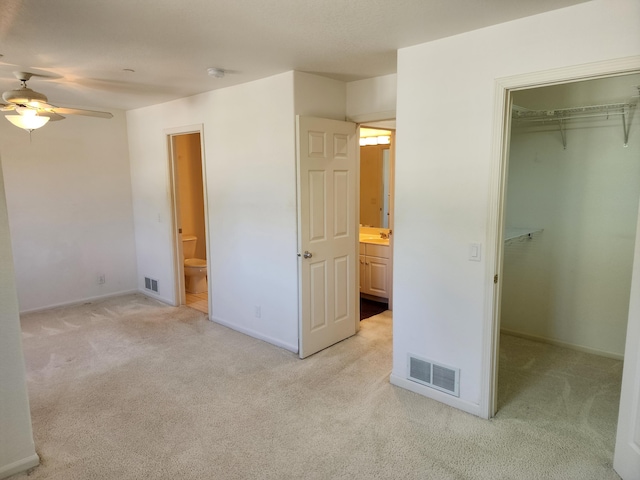 unfurnished bedroom featuring visible vents, a walk in closet, and light carpet