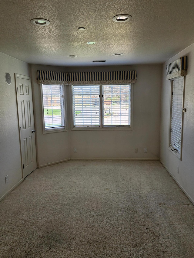 carpeted empty room featuring baseboards and a textured ceiling