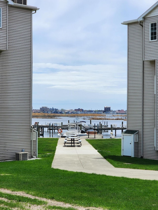 view of community featuring a yard, a water view, and a boat dock