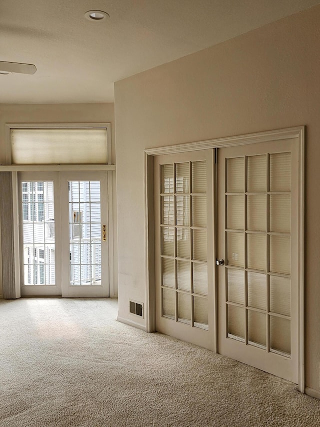 entryway featuring carpet flooring, ceiling fan, and visible vents