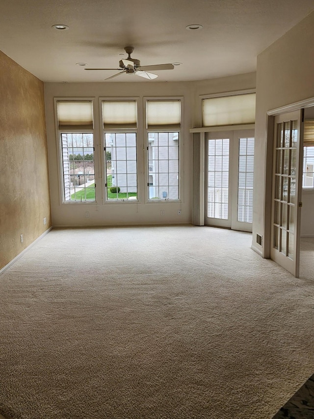 empty room with carpet floors, a ceiling fan, and baseboards