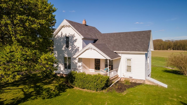 back of house featuring a porch, a shingled roof, a yard, and a chimney