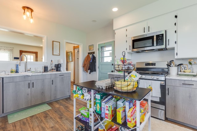 kitchen with white cabinetry, appliances with stainless steel finishes, a sink, and light wood-style floors