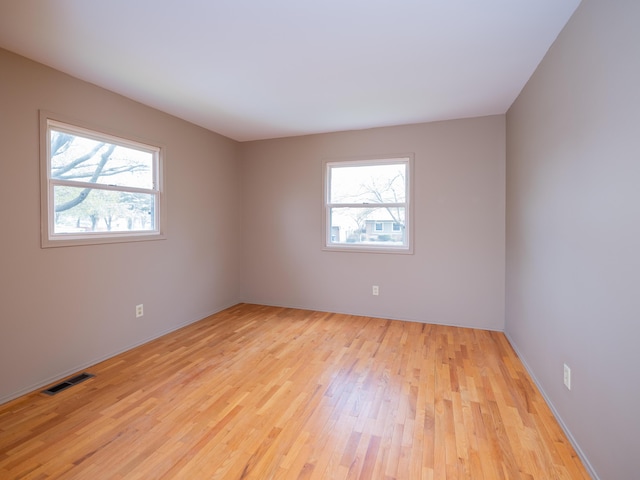 spare room featuring baseboards, visible vents, and light wood-style floors