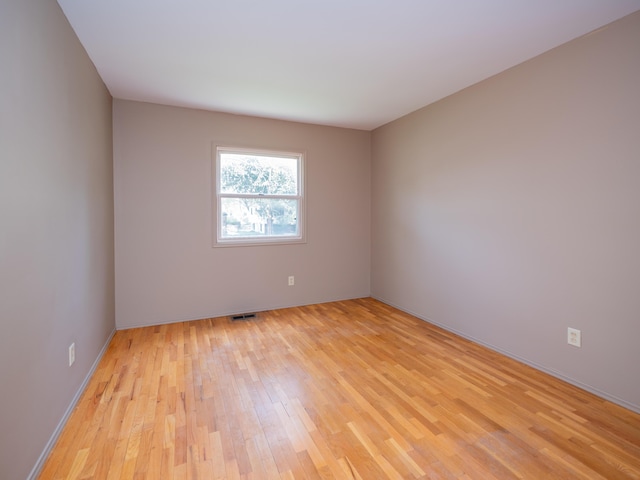empty room featuring baseboards, light wood-style flooring, and visible vents