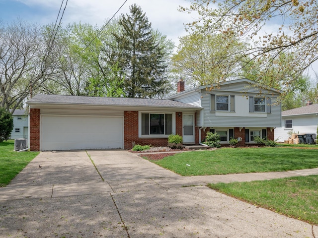 tri-level home with a front lawn, a chimney, brick siding, concrete driveway, and an attached garage