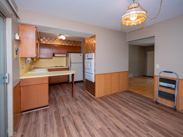 kitchen featuring light countertops, light wood finished floors, a warming drawer, and white appliances