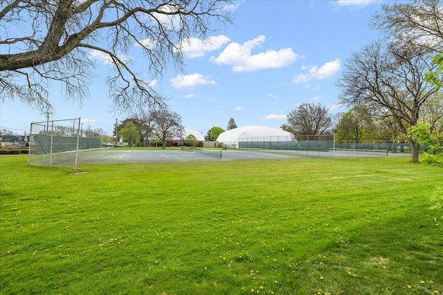view of yard with a tennis court and fence
