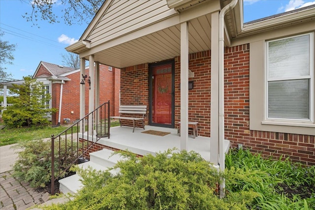 view of exterior entry with brick siding and covered porch