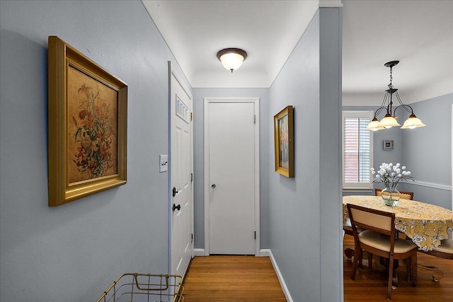 interior space with an inviting chandelier, baseboards, and wood finished floors