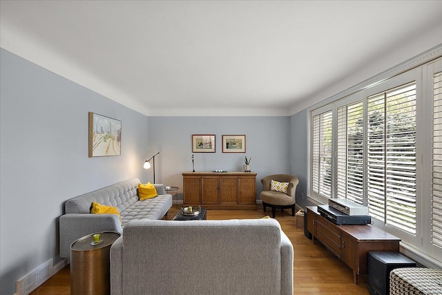 living room featuring visible vents, light wood finished floors, and baseboards