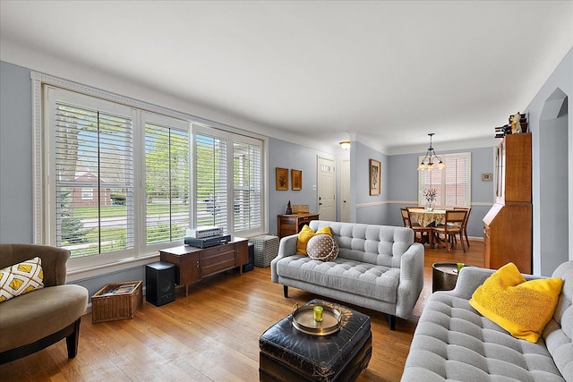 living area with light wood finished floors, a notable chandelier, and a healthy amount of sunlight