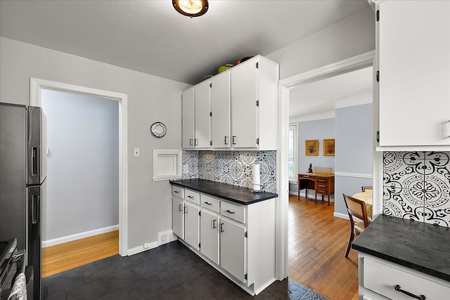 kitchen with freestanding refrigerator, decorative backsplash, white cabinets, and dark countertops
