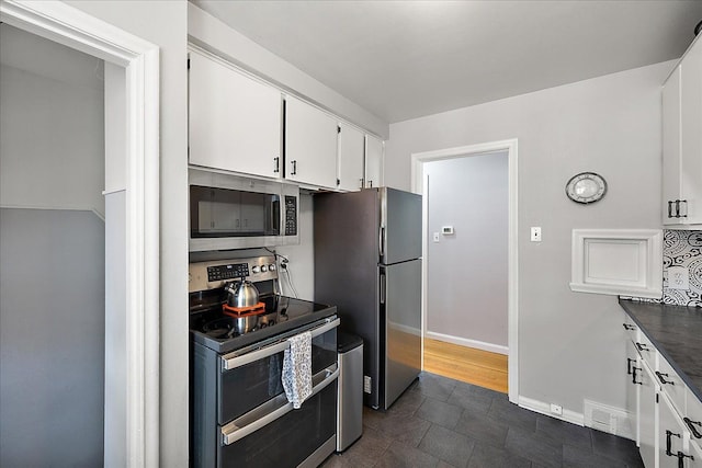 kitchen featuring visible vents, dark countertops, appliances with stainless steel finishes, baseboards, and white cabinetry