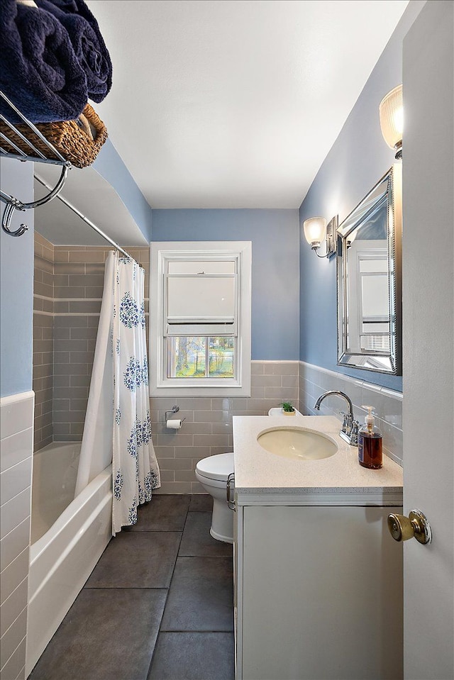 full bath with shower / tub combo with curtain, vanity, toilet, tile patterned floors, and tile walls