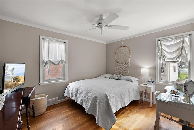 bedroom featuring visible vents, ornamental molding, light wood-style flooring, and baseboards