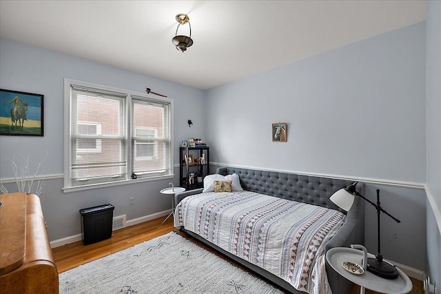 bedroom with baseboards, wood finished floors, and visible vents