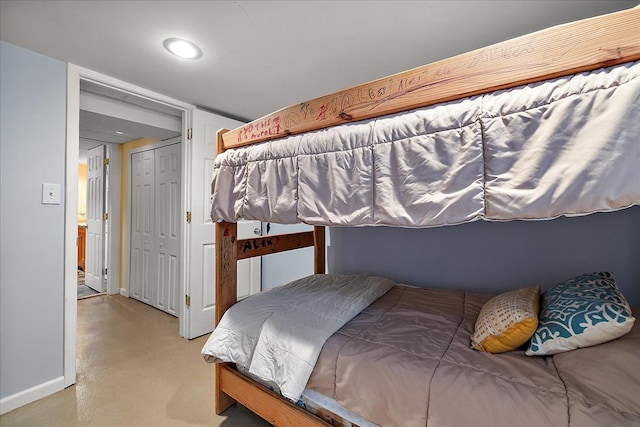 bedroom with recessed lighting, baseboards, finished concrete floors, and a closet
