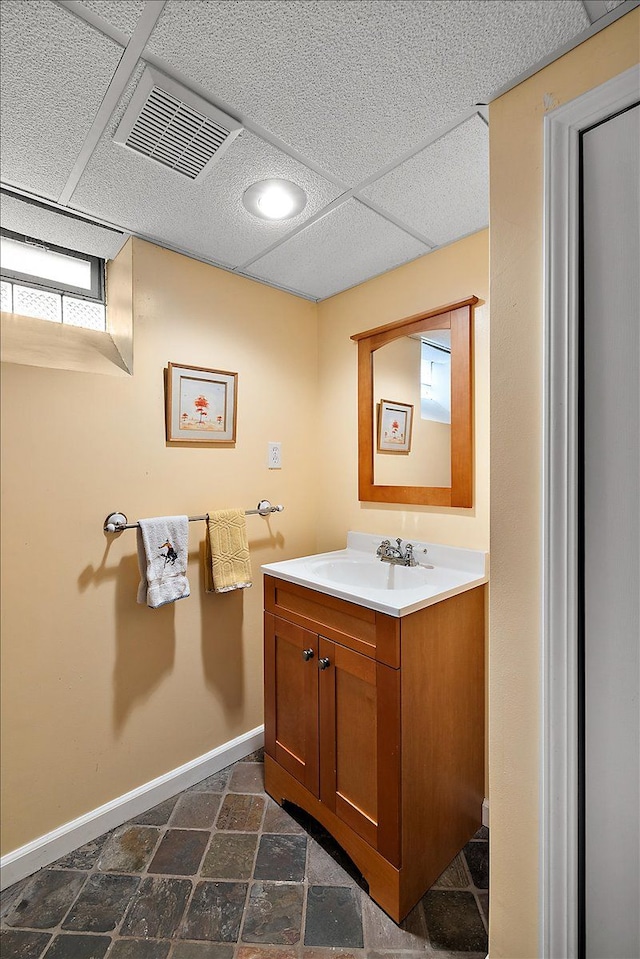bathroom with baseboards, stone finish floor, vanity, and visible vents