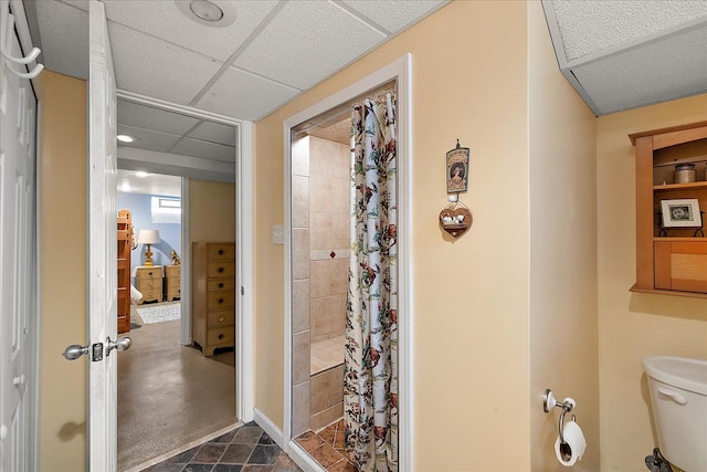 full bath featuring stone finish floor, toilet, and tiled shower